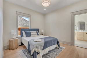 Bedroom with light wood-style flooring, connected bathroom, and recessed lighting