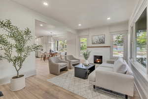Living area with light wood-style flooring, a lit fireplace, and recessed lighting