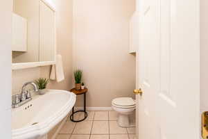 Half bath with overhead storage for added convenience, just off the laundry room
