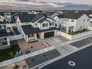Modern farmhouse with stone siding, a mountain view, driveway, a gate, and an attached garage