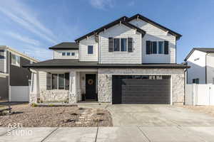 Craftsman-style house with stone siding, covered porch, driveway, and an attached garage