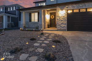 Entrance to property featuring stone siding, a porch, and driveway