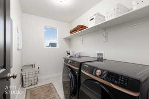 Laundry room featuring washing machine and dryer and light tile patterned floors