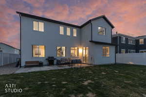 Back of house at dusk featuring a fenced backyard, a patio area, and stucco siding