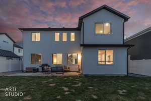 Back of house at dusk featuring a fenced backyard, stucco siding, a patio, and an outdoor lounge area