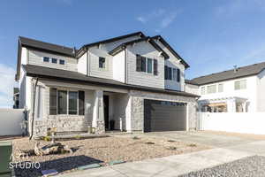 View of front of property with an attached garage, driveway, covered porch, and stone siding