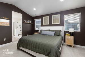 Bedroom with vaulted ceiling, light carpet, ensuite bathroom, and recessed lighting