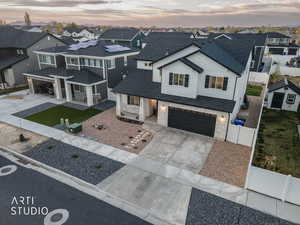 View of front facade with stone siding, driveway, a garage, and a residential view