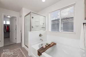 Bathroom featuring a spacious closet, a bath, a shower stall, and light tile patterned floors