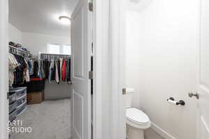 Bathroom with a walk in closet and light carpet