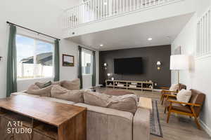 Living area featuring a high ceiling, light wood-type flooring, and recessed lighting