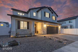 View of front of house featuring stone siding, a porch, concrete driveway, and a garage