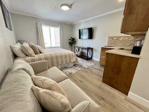Bedroom with light wood-style flooring and crown molding