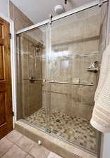 Bathroom with a textured ceiling, a stall shower, and tile patterned floors