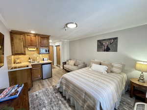 Bedroom featuring ornamental molding, stainless steel refrigerator, and light wood-style floors
