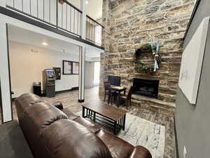 Living area featuring a high ceiling, a stone fireplace, wood finished floors, and recessed lighting