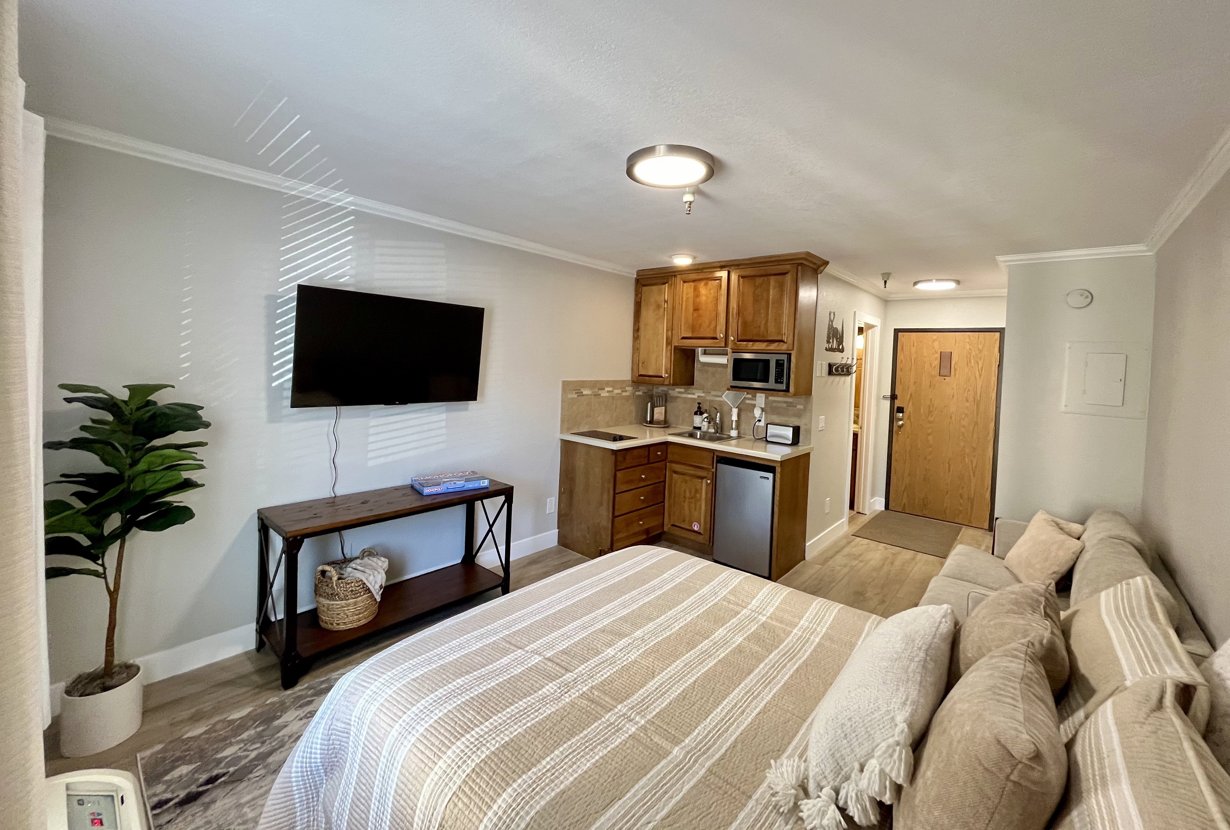 Bedroom with ornamental molding, light wood finished floors, and stainless steel refrigerator