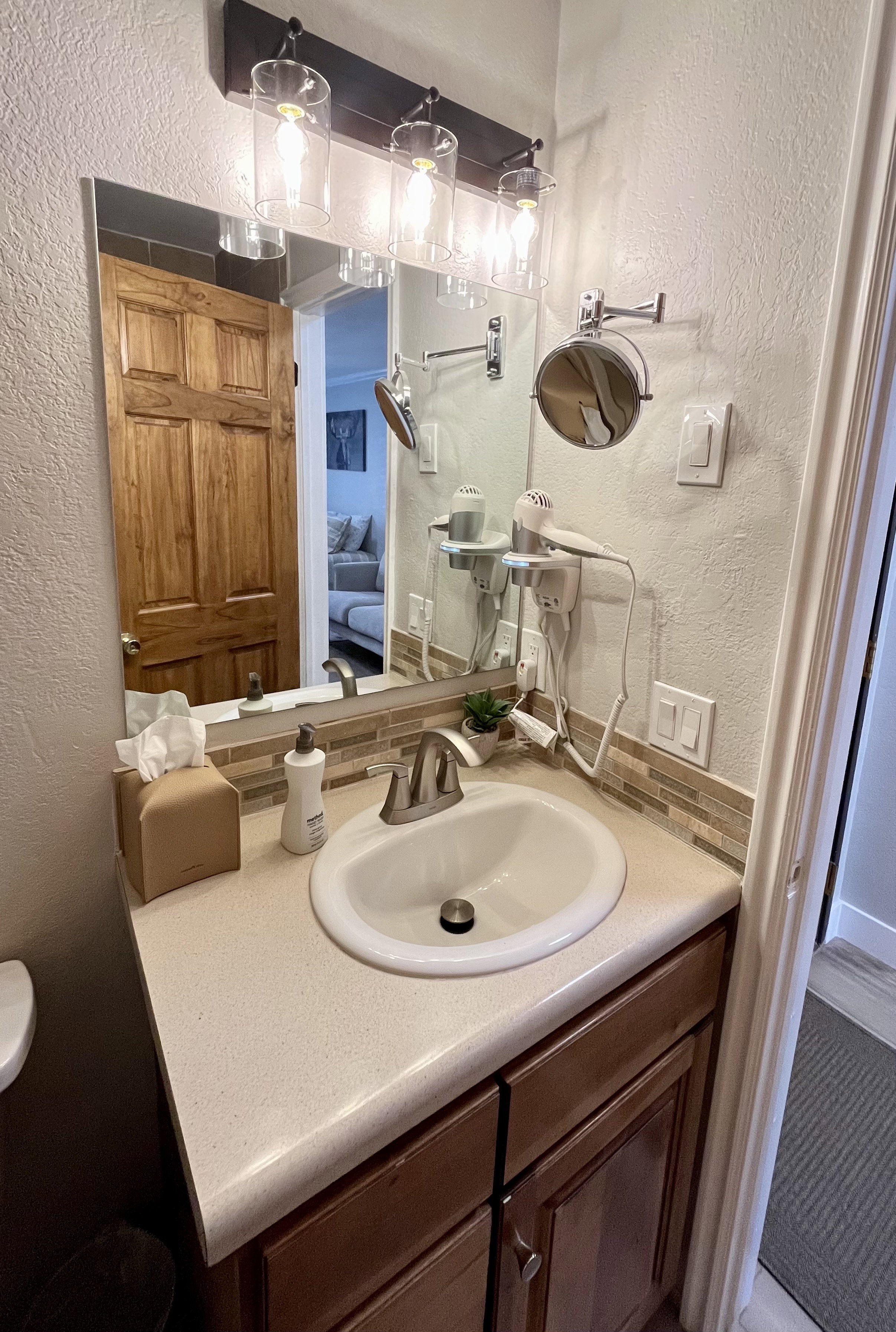 Ensuite bathroom with a textured wall, vanity, and backsplash