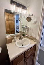 Ensuite bathroom with a textured wall, vanity, and backsplash