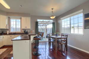 Kitchen with dark countertops, white cabinetry, a peninsula, hanging light fixtures, and a breakfast bar area