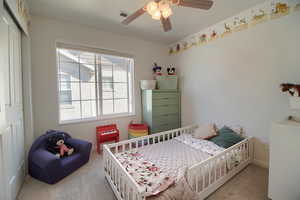 Carpeted bedroom with ceiling fan and a closet