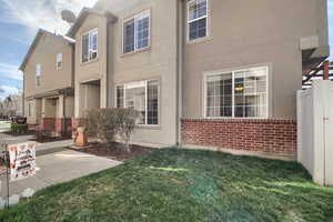 View of property exterior featuring a lawn, stucco siding, and brick siding