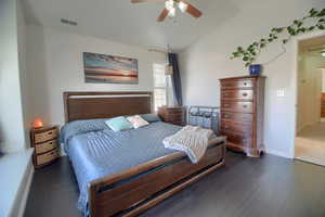 Bedroom with vaulted ceiling, dark wood-style flooring, and a ceiling fan