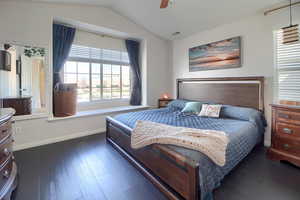 Owner's suite featuring dark wood-style floors, vaulted ceiling, and ceiling fan