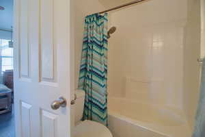 Full bathroom featuring toilet and shower / bath combo with shower curtain