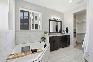 Primary bathroom featuring double vanity, a garden tub, and 2 spacious walk-in closets