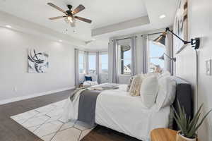 Primary bedroom featuring a tray ceiling, wood finished floors, recessed lighting, and ceiling fan