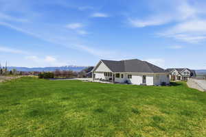 Back of house featuring a mountain view, a patio area, and a lawn