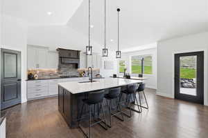 Dual tone kitchen featuring two tone color scheme, granite countertops, a breakfast bar, tasteful backsplash, and hardwood flooring