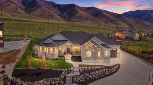Craftsman-style home featuring driveway, a porch, a mountain view, and stone siding