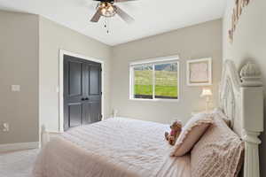 Carpeted bedroom with a ceiling fan and a closet