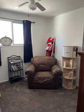 Bedroom/office room with dark colored carpet and ceiling fan