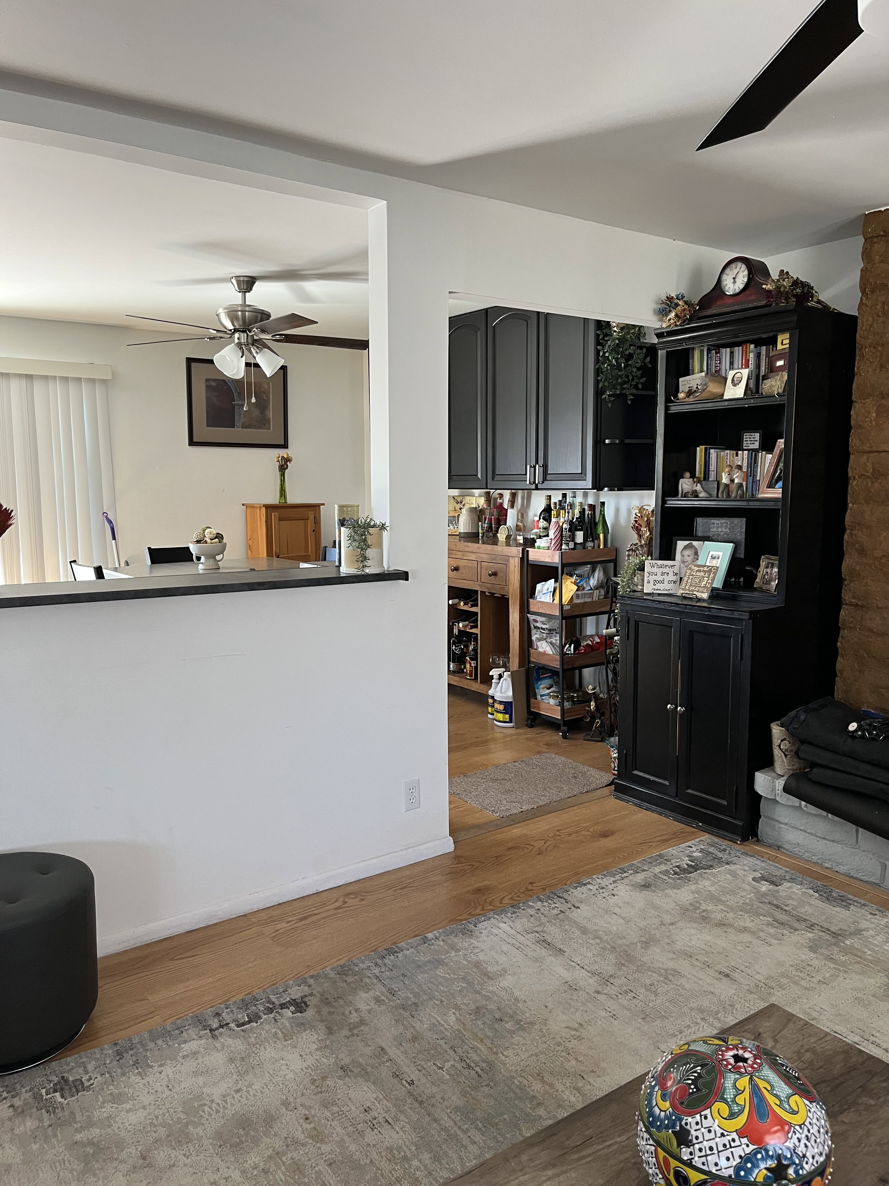 Living room with ceiling fan and wood finished floors looking into dining/kitchen