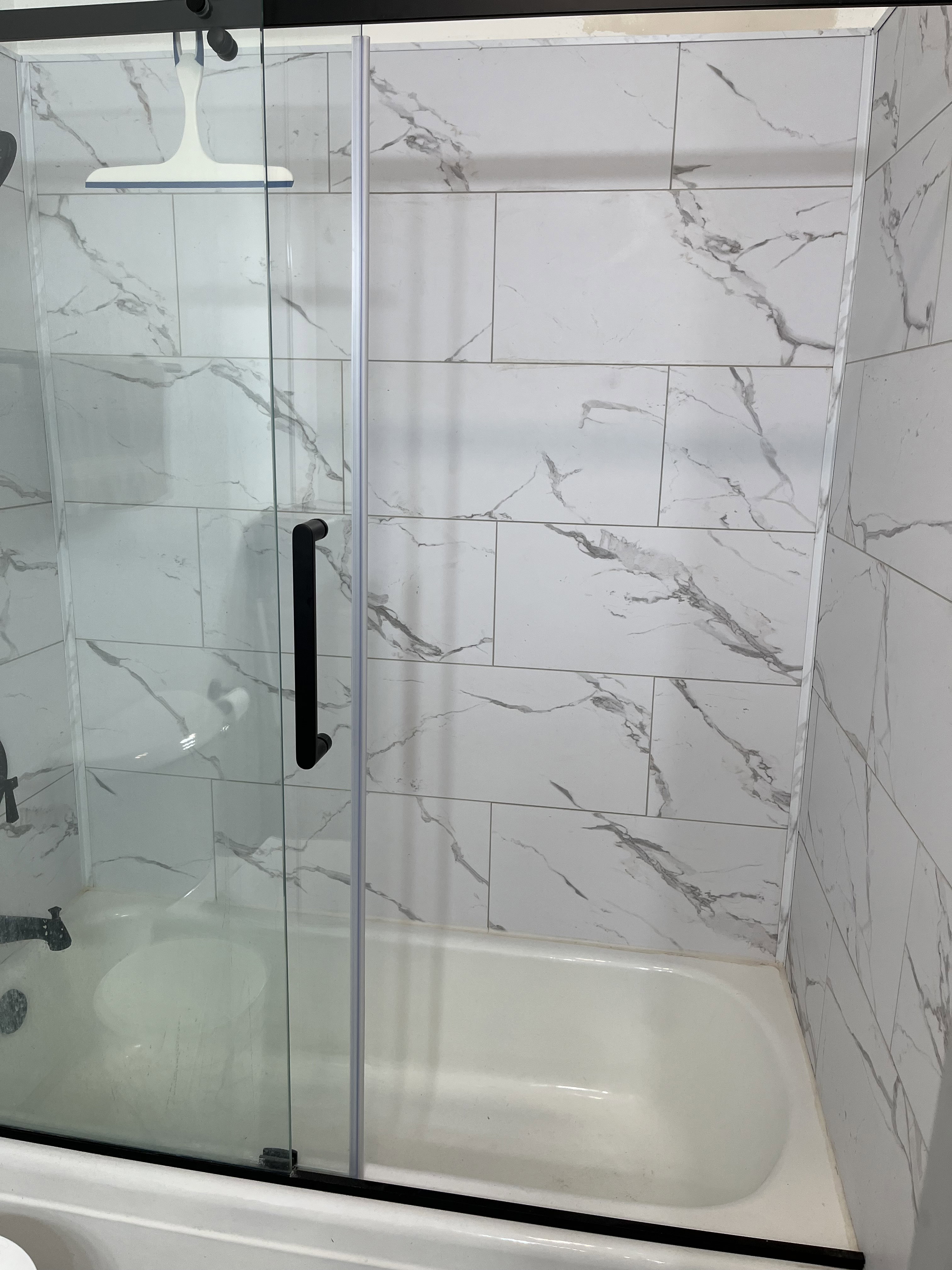 Full bath with a marble finish shower / bath combo