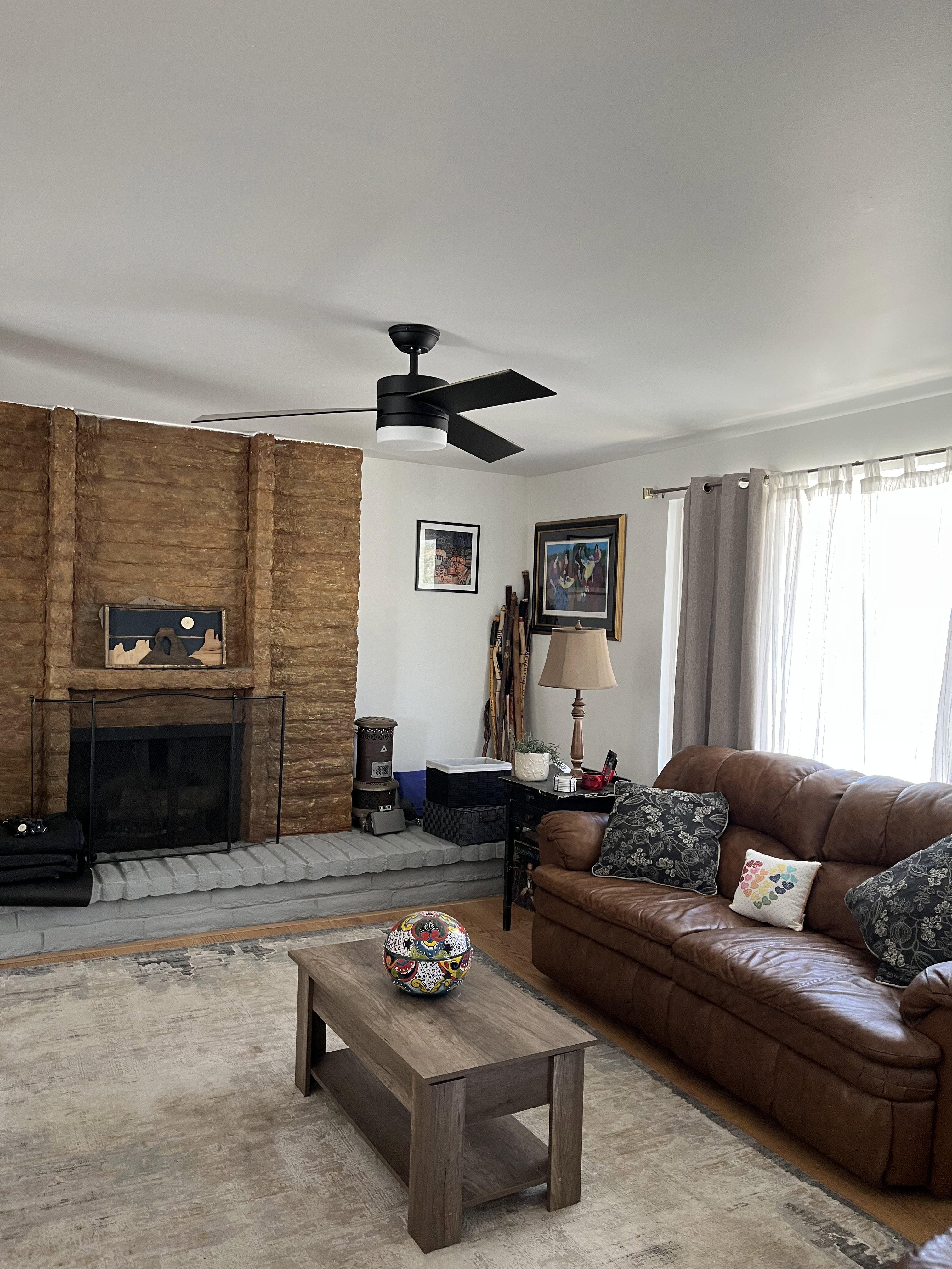 Living room with a ceiling fan, a fireplace, and wood finished floors