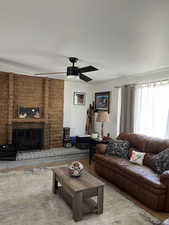 Living room with a ceiling fan, a fireplace, and wood finished floors