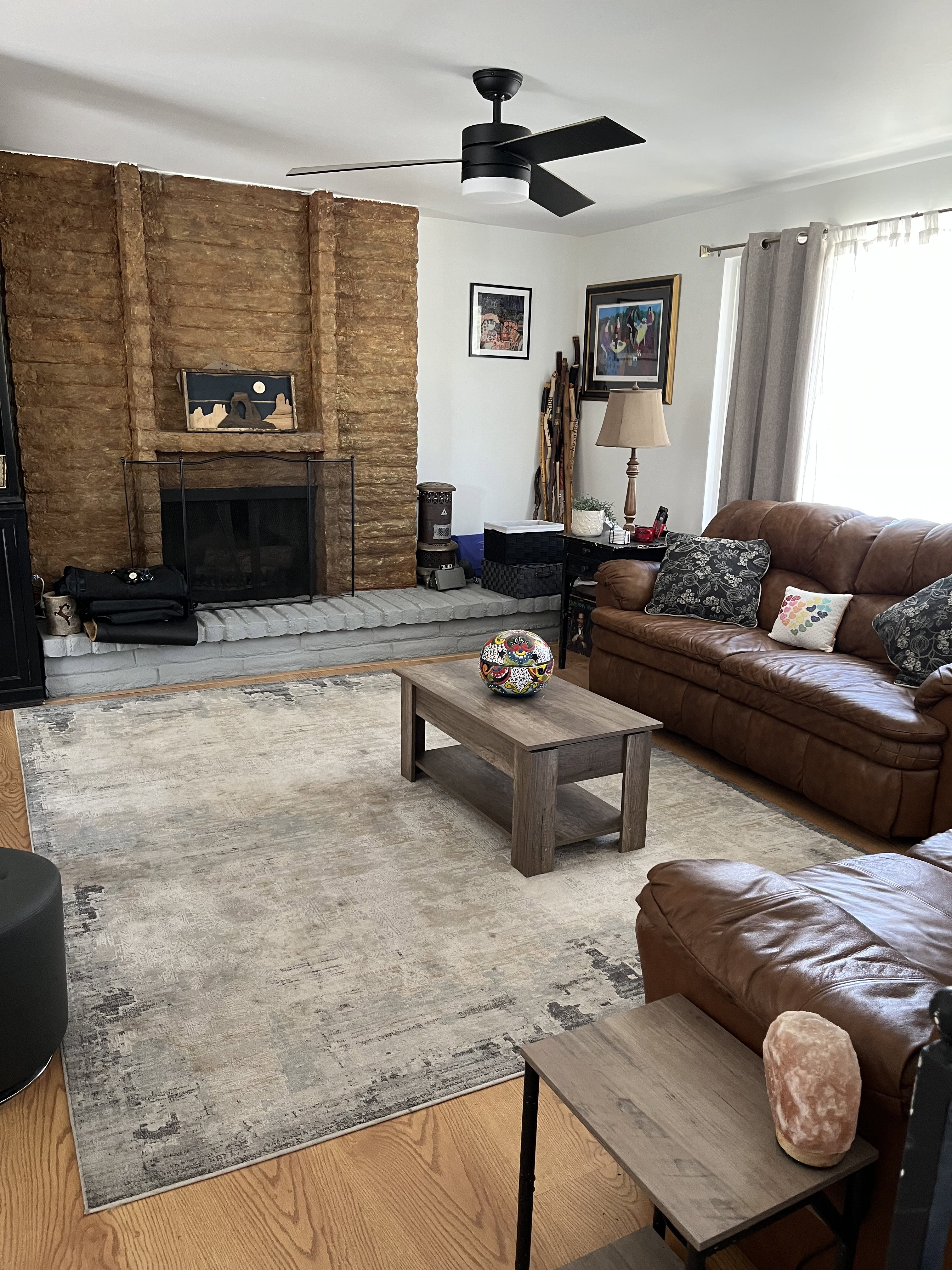 Living area with a ceiling fan, wood finished floors, and a fireplace