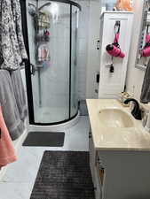 Bathroom with vanity, marble look tiles, and a marble finish shower