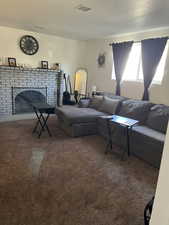 Carpeted living area with a fireplace, a textured ceiling, and above ground windows