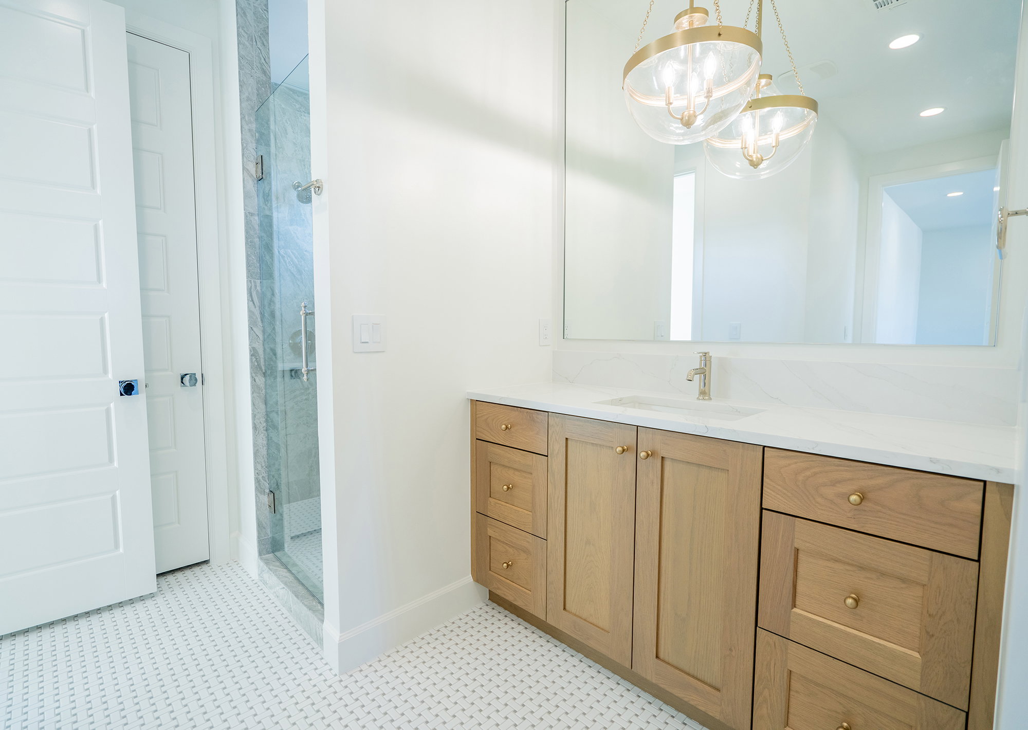 Full bath with vanity, a stall shower, and suspended lighting