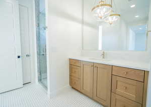 Full bath with vanity, a stall shower, and suspended lighting