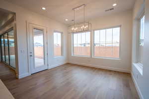 Unfurnished dining area with suspended lighting and light wood-style flooring