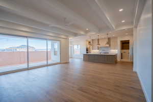 Unfurnished living room with beamed ceiling, a ceiling fan, light wood-style flooring, suspended lighting, and crown molding