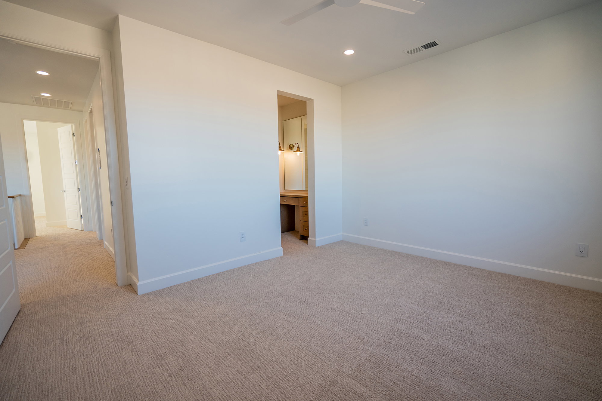 Unfurnished bedroom with built in desk, light carpet, recessed lighting, a ceiling fan, and ensuite bath