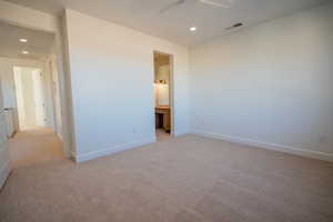 Unfurnished bedroom with built in desk, light carpet, recessed lighting, a ceiling fan, and ensuite bath