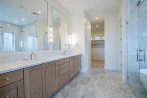 Bathroom featuring a shower stall, double vanity, a spacious closet, recessed lighting, and light marble finish flooring
